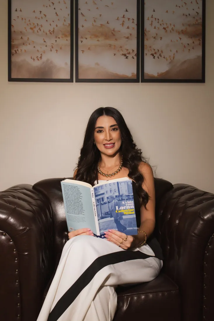 Jennifer na poltrona chesterfield lendo A vida com Lacan, de Catherine Millot
