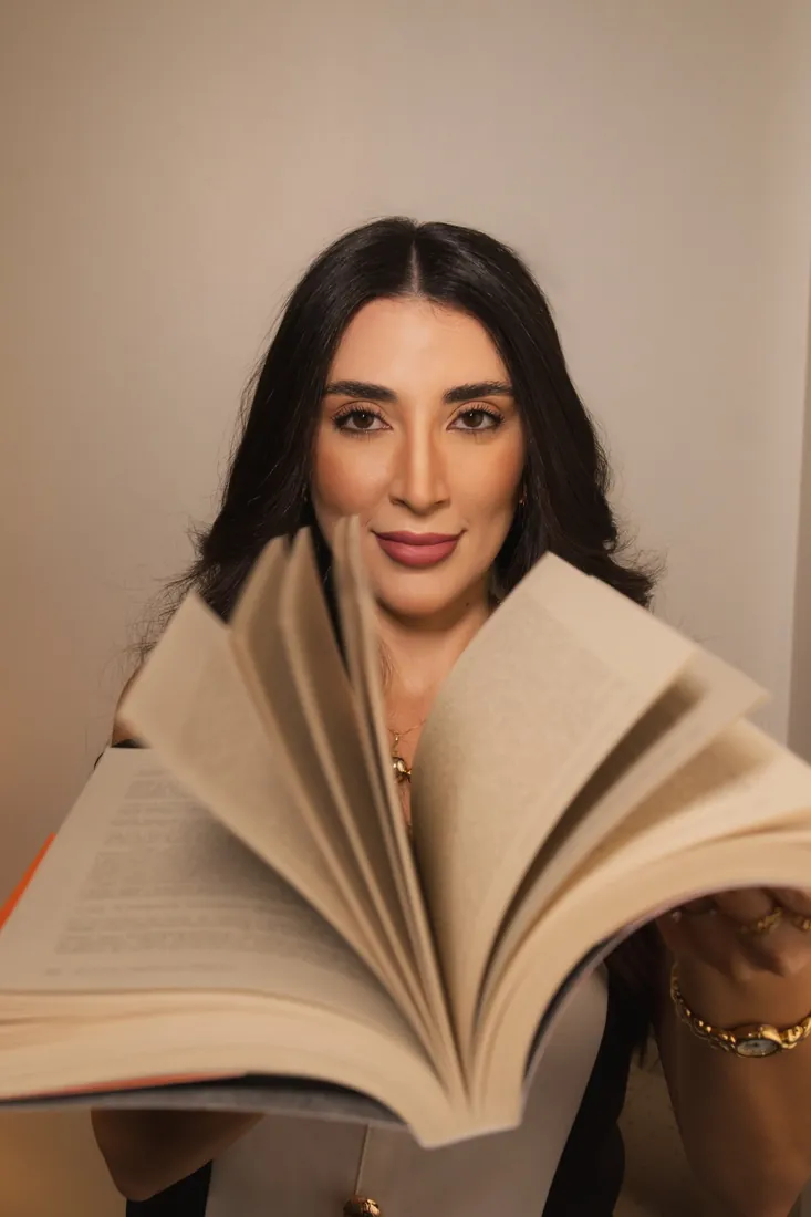 Jennifer Guimarães folheando um livro em direção à câmera